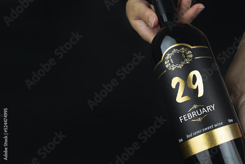 February 29th. Day 29 of month, Calendar date. Hands hold bottle of red wine with a calendar date on label. Winter month, day of the year concept.