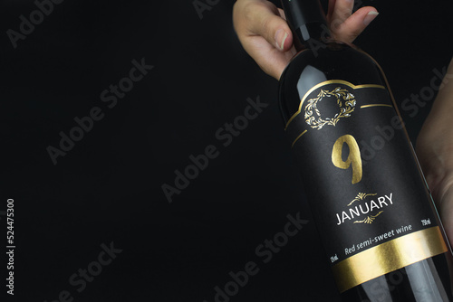 January 9th. Day 9 of month, Calendar date. Hands hold bottle of red wine with a calendar date on label. Winter month, day of the year concept. © Alexa Mat
