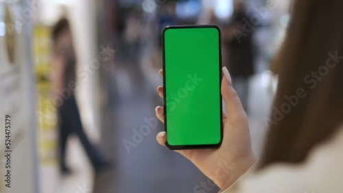 View of a woman on the phone with a green screen for copy space. Chromakey mockup without tracking markers. Close up.Young woman standing in a shopping mall with a smartphone. Busy shopping center photo