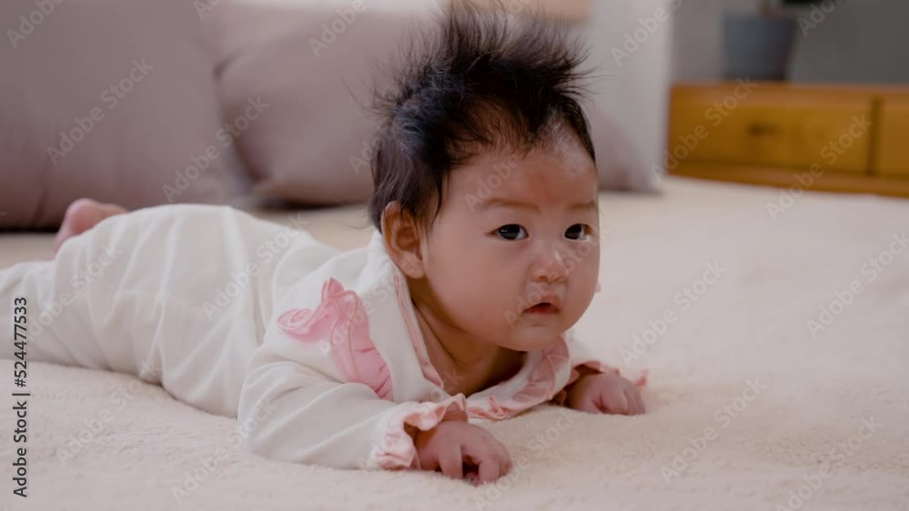 4K, Close Up Asian girl lying face down in bed in her bedroom, after waking up, her head is raised looking for her mother. Asian newborn baby 3 months old with black hair 4K, Close Up Asian girl lying face down in bed in her bedroom, after waking up, her head is raised looking for her mother. Asian newborn baby 3 months old with black hair