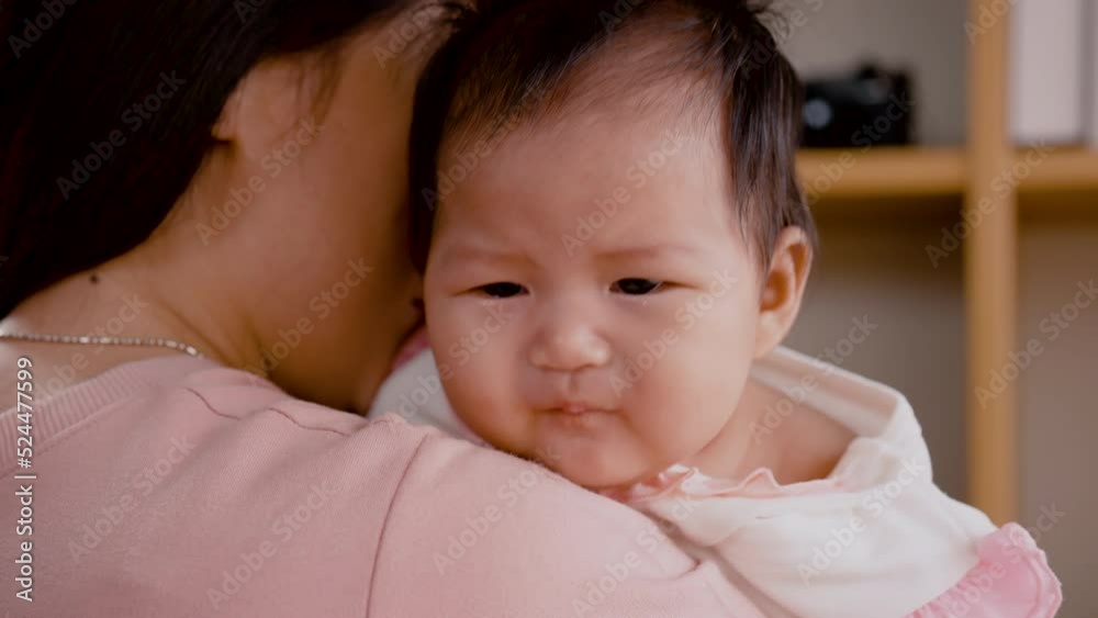 4K, Close Up A 3-month-old newborn Asian girl is crying on her mother's shoulder. A single mother is holding her child, comforting her not to cry, and caring closely with love and warmth in bedroom. 4K, Close Up A 3-month-old newborn Asian girl is crying on her mother's shoulder. A single mother is holding her child, comforting her not to cry, and caring closely with love and warmth in bedroom.