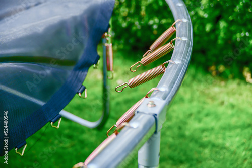 Disassembled trampoline in the yard after purchase. Assembly and installation in a private yard on a green lawn.