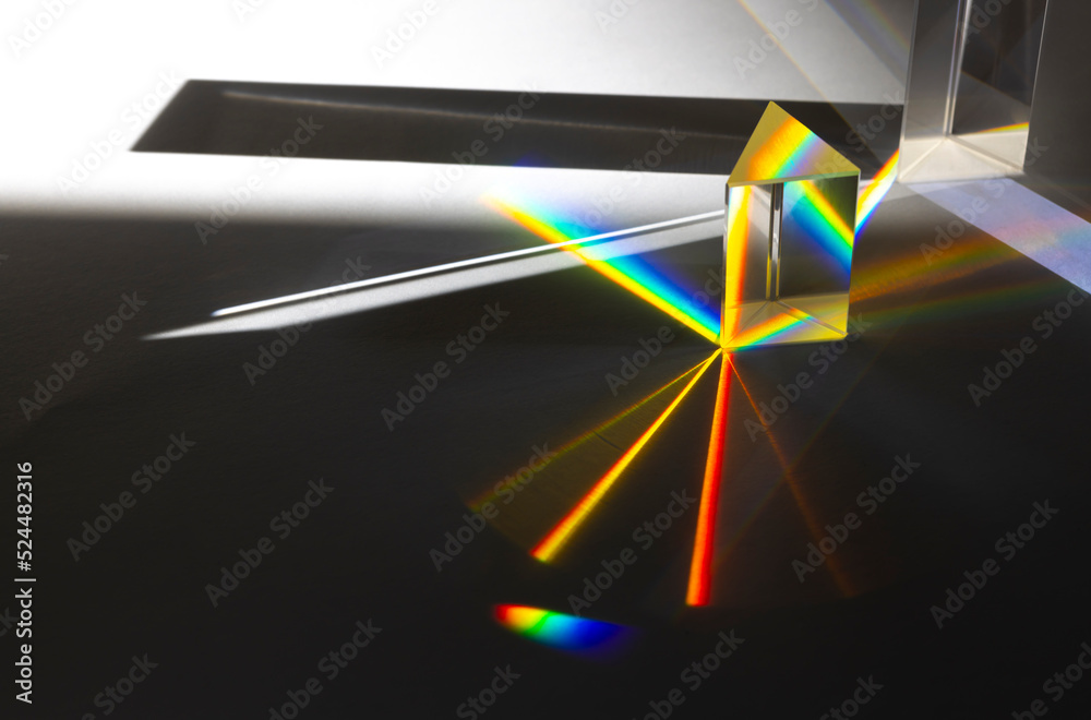 Photo of two triangular Prisms dispersing sun beam splitting into a spectrum on white background - obrazy, fototapety, plakaty 