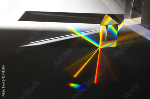 Photo of two triangular Prisms dispersing sun beam splitting into a spectrum on white background