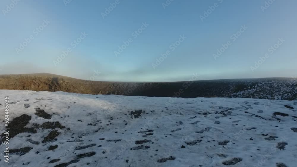 aerial shots of a lagoon in an inactive volcano, frozen and with snow on the stones on the shores. aerial shots of a lagoon in an inactive volcano, frozen and with snow on the stones on the shores.