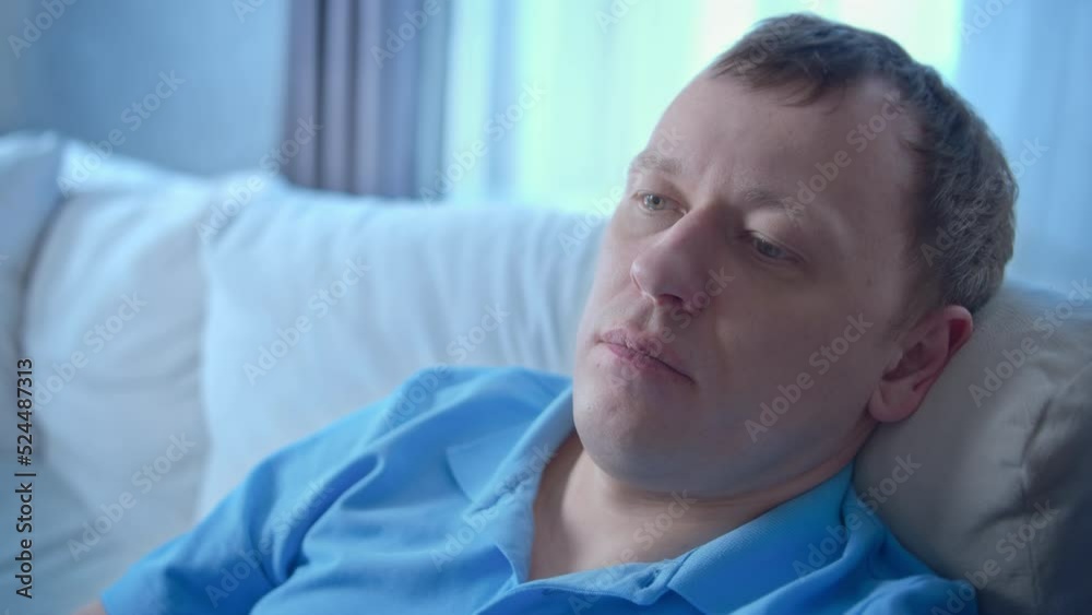Portrait of a young man with a tired face sitting on a sofa, close-up Portrait of a young man with a tired face sitting on a sofa, close-up