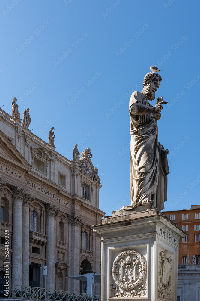A bird sits on the head of a statue in front of Saint Peter's Basilica in Rome