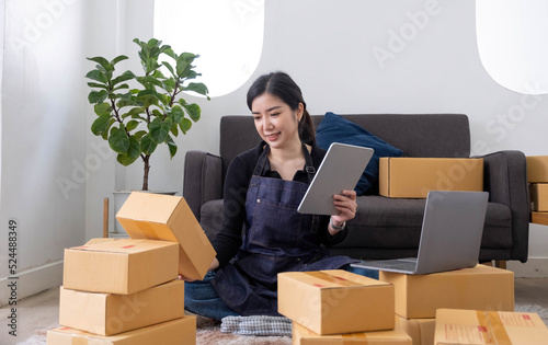 Starting small businesses SME owners female entrepreneurs Use a laptop or notebook to receive and review orders online to prepare to pack boxes, sell to customers, SME online business ideas.