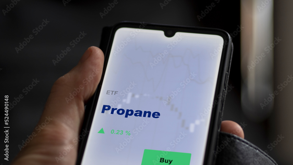 An investor's analyzing the propane etf fund on a screen. A phone shows the prices of gas ETF	

