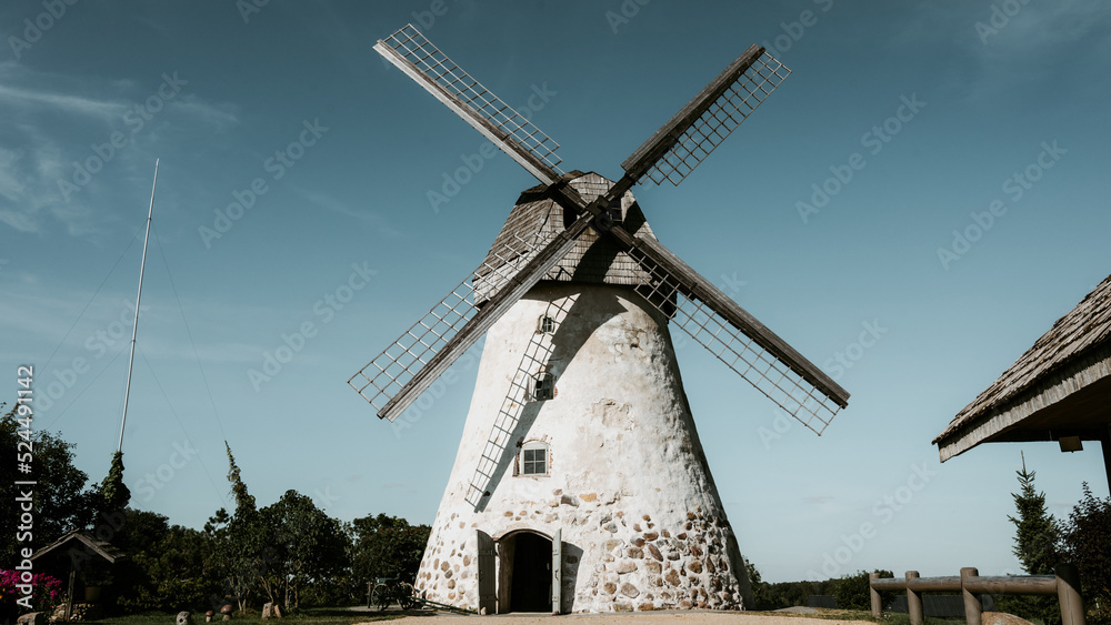 Obraz premium Dutch-type windmill in Araisi, Latvia. Sunny summer day. Old Europe style. Blue sky. Green grass.
