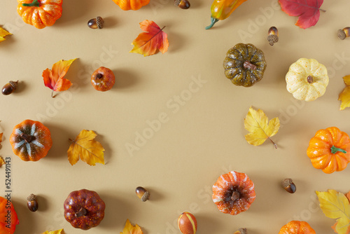 Minimal autumn nature composition. Pumpkins and colorful autumn leaves on beige background with copy space. Flat lay. Autumn seasonal creative concept.