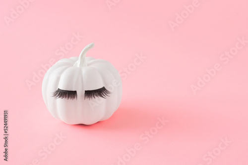 White Halloween pumpkin with eyelashes on pink pastel background. Minimal Holiday season concept. photo