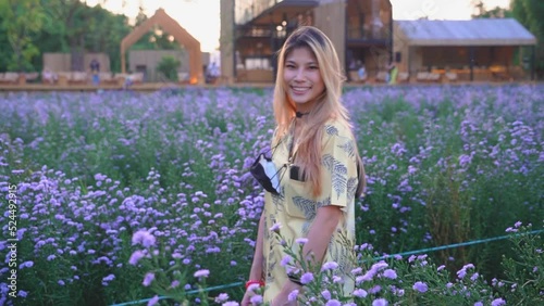 Asian woman is wearing face mask in a flower meadow outdoor for freedom in pandemic concept.