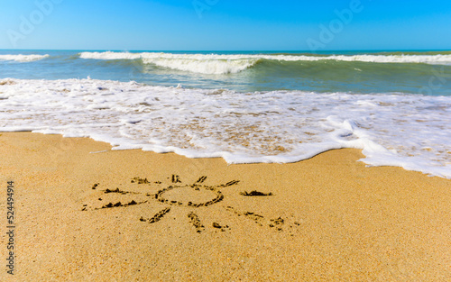 Drawn sun on the sandy seashore. Summer vacation concept. Selective focus on the figure.