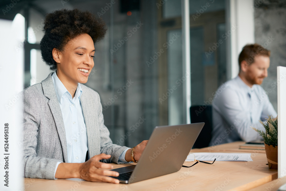 Fototapeta premium Happy black businesswoman works on laptop in office.