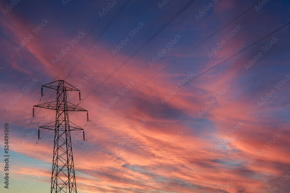 Silhouette High voltage electric pylon during a vivid  sunset during summer months