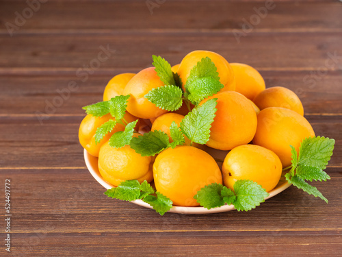 ripe apricots on a plate on a wooden table.