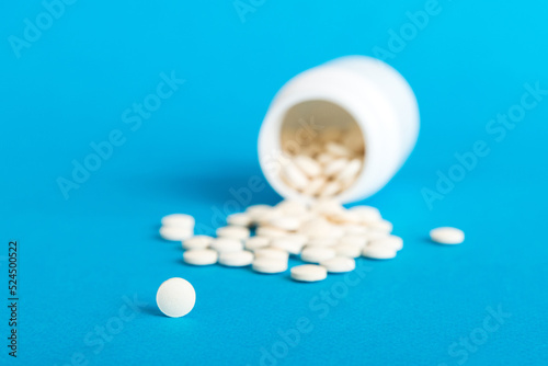 Medicine bottle and white pills spilled on a light background. Medicines and prescription pills flat lay background. White medical pills and tablets spilling out of a drug bottle