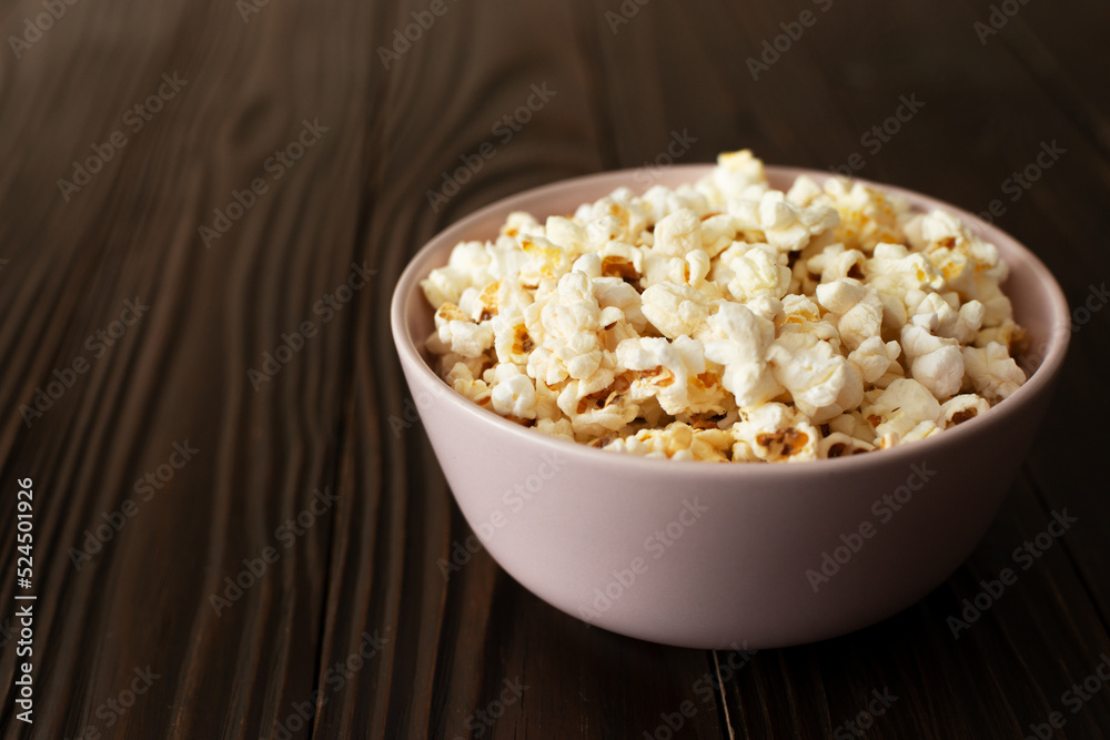 Bowl with popcorn on dark wooden table with copy-space