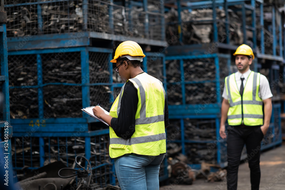 Plus size black female worker wearing safety hard hat helmet inspecting old car parts stock while working in automobile large warehouse Plus size black female worker wearing safety hard hat helmet inspecting old car parts stock while working in automobile large warehouse
