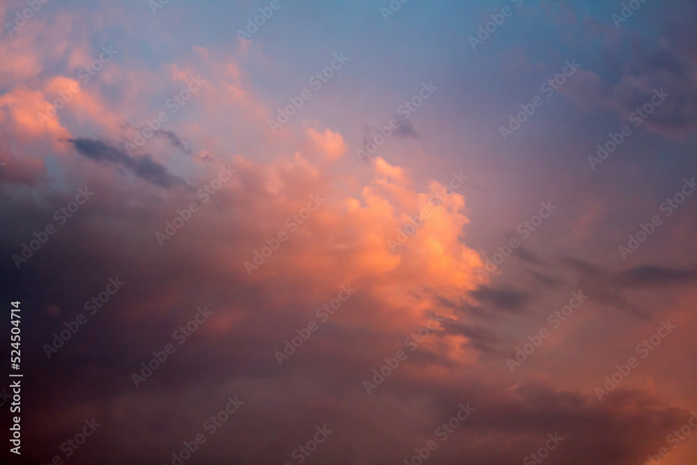 Sunset sky with dark blue clouds through which the rays of the sun break through