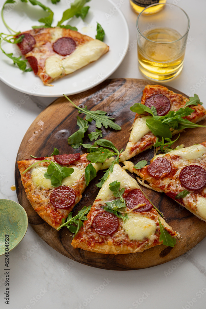 Sliced italian salami pizza on wooden board top view on stone surface Sliced italian salami pizza on wooden board top view on stone surface