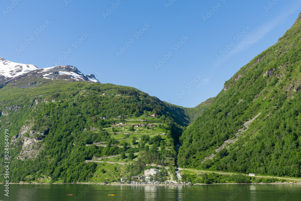 Geiranger Fjord surrounded by high green, snow-capped mountains in Norway