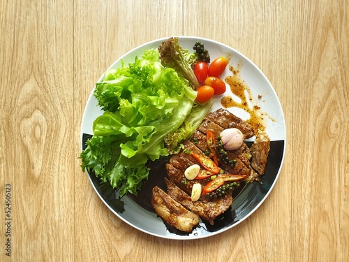 фотографія Grilled pork steak with salad on the black and white plate