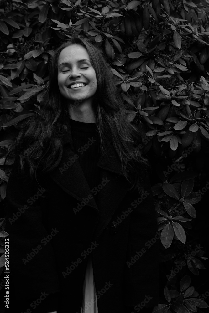 Yong girl in the autumn park on the background of plant leaves. Black and white emotional portraits