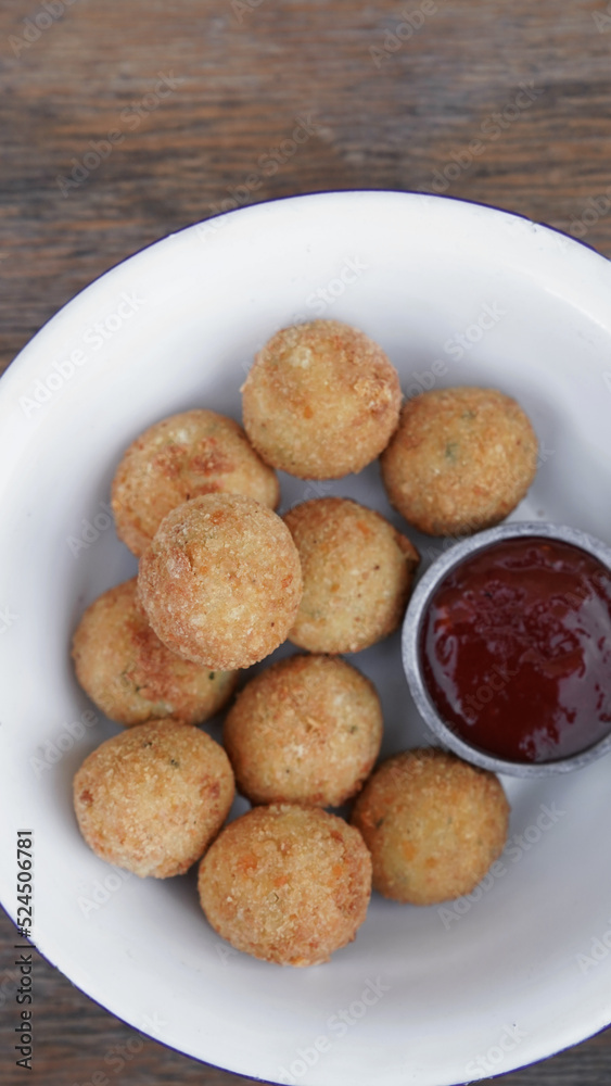 Fritters. Top view of potato and mozzarella cheese croquettes with sweet chili dipping sauce, in a white bowl on the wooden table. Fritters. Top view of potato and mozzarella cheese croquettes with sweet chili dipping sauce, in a white bowl on the wooden table.