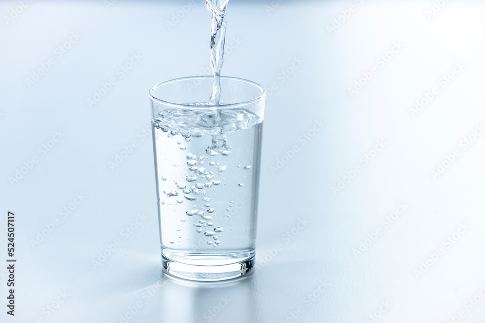 テーブルに置いたコップに水を注ぐ
テーブルに置いたコップに水を注ぐ
