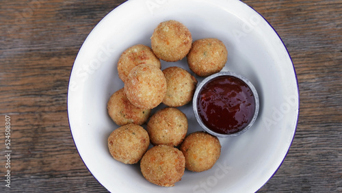 Cheese balls. Top view of potato and mozzarella cheese croquettes with sweet chili dipping sauce  in a white bowl on the wooden table.