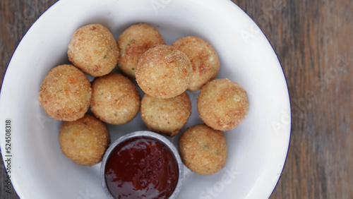 Fritters. Top view of potato and mozzarella cheese croquettes with sweet chili dipping sauce, in a white bowl on the wooden table. 