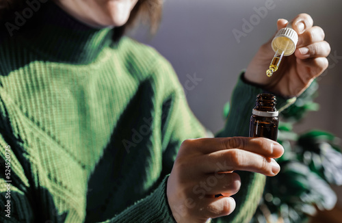 Woman holding a dropper of sublingual cbd cannabis hemp oil - Alternative medical treatment