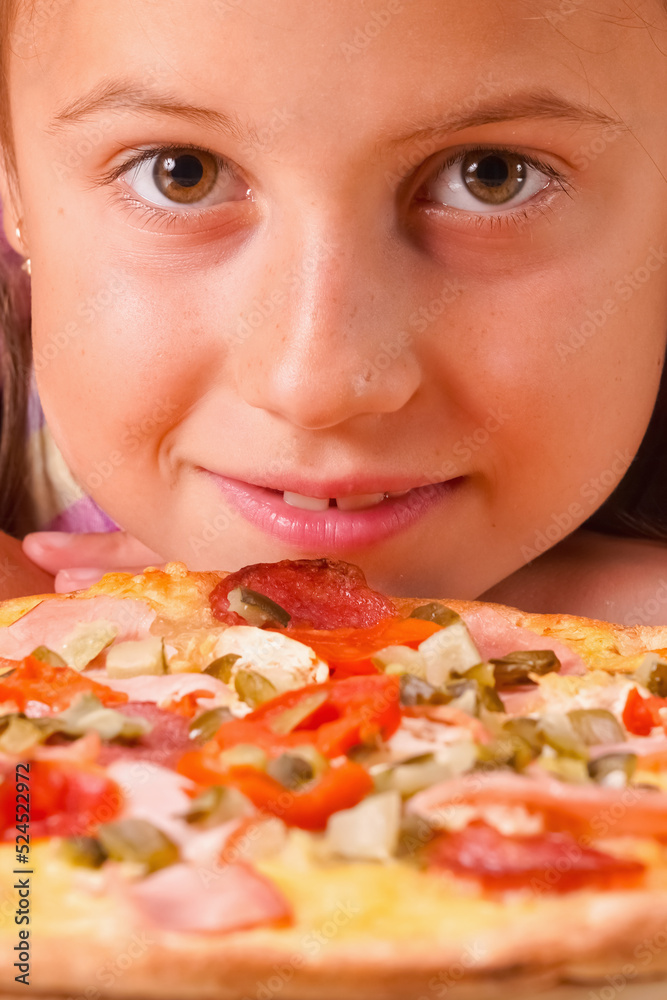 Kids' pizza. Close up portrait of happy young beautiful child girl holding pizza. Vertical image.