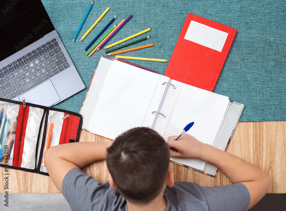 Top view of child studying at home with notebook and laptop. Blank copy space Top view of child studying at home with notebook and laptop. Blank copy space