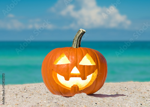 Happy Halloween. Pumpkin Jack-o'-lantern on the beach. Jack o lantern for Halloween party. Autumn season. Blue ocean on background. Autumn season. Florida beach. Copy space. © artiom.photo