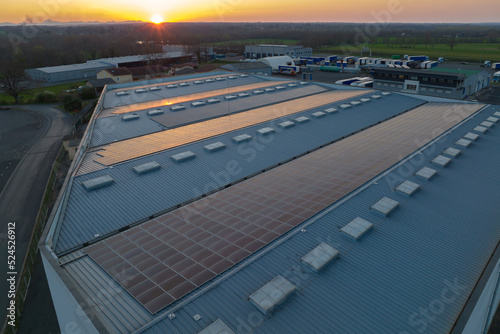 Blue photovoltaic solar panels mounted on building roof for producing clean ecological electricity at sunset. Production of renewable energy concept