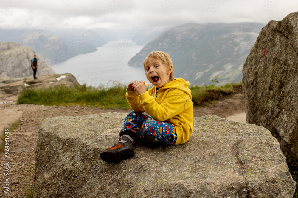 Family, enjoying the hike to Preikestolen, the Pulpit Rock in Lysebotn, Norway on a rainy day, toddler climbing with his pet dog the one of the most scenic fjords Family, enjoying the hike to Preikestolen, the Pulpit Rock in Lysebotn, Norway on a rainy day, toddler climbing with his pet dog the one of the most scenic fjords