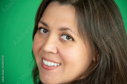 close-up portrait of a plump confident smiling woman looking at the camera  against a green background