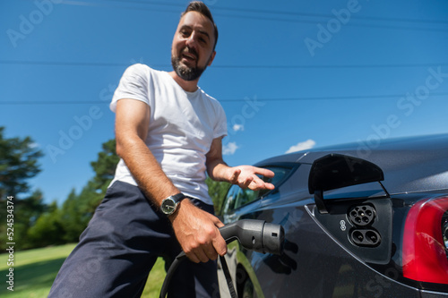 Caucasian man connect charger to electric car. 