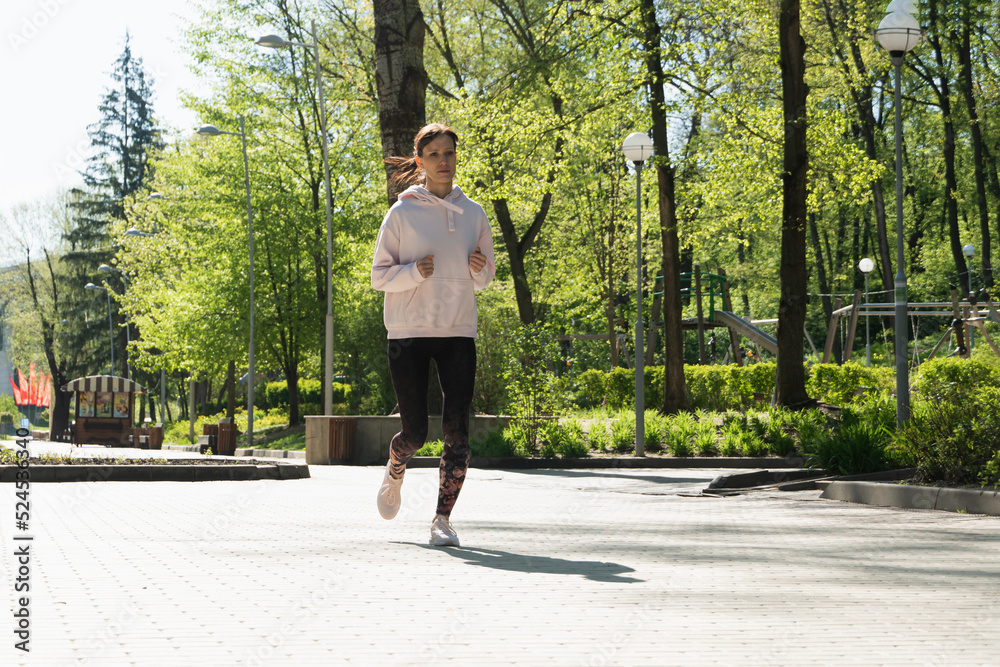 Fototapeta premium Brunette runner woman runs in the park jogging, concept of training exercise