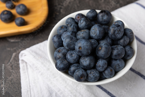 Blueberries in a ceramic bowl on a black textured background. Ripe and fresh blueberries. Vitamins. Healthy food. Juicy berry.Copy space.Place for text