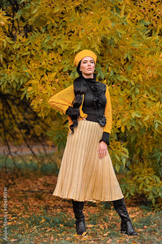 a beautiful brunette with makeup in a yellow beret and yellow jacket walks in the park in autumn. a beautiful brunette with makeup in a yellow beret and yellow jacket walks in the park in autumn.