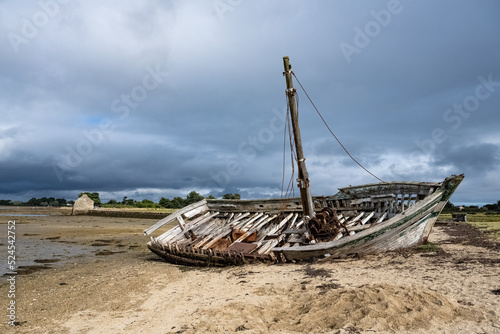 Brittany, Ile d’Arz in the Morbihan gulf, a wreck ship on the beach, with the traditional tide mill in background 