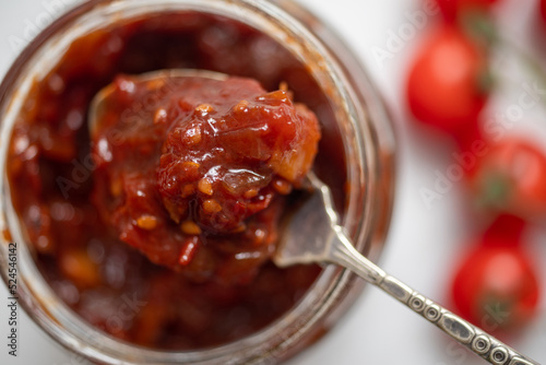 Homemade spicy tomato chutney on a spoon from a jar. photo