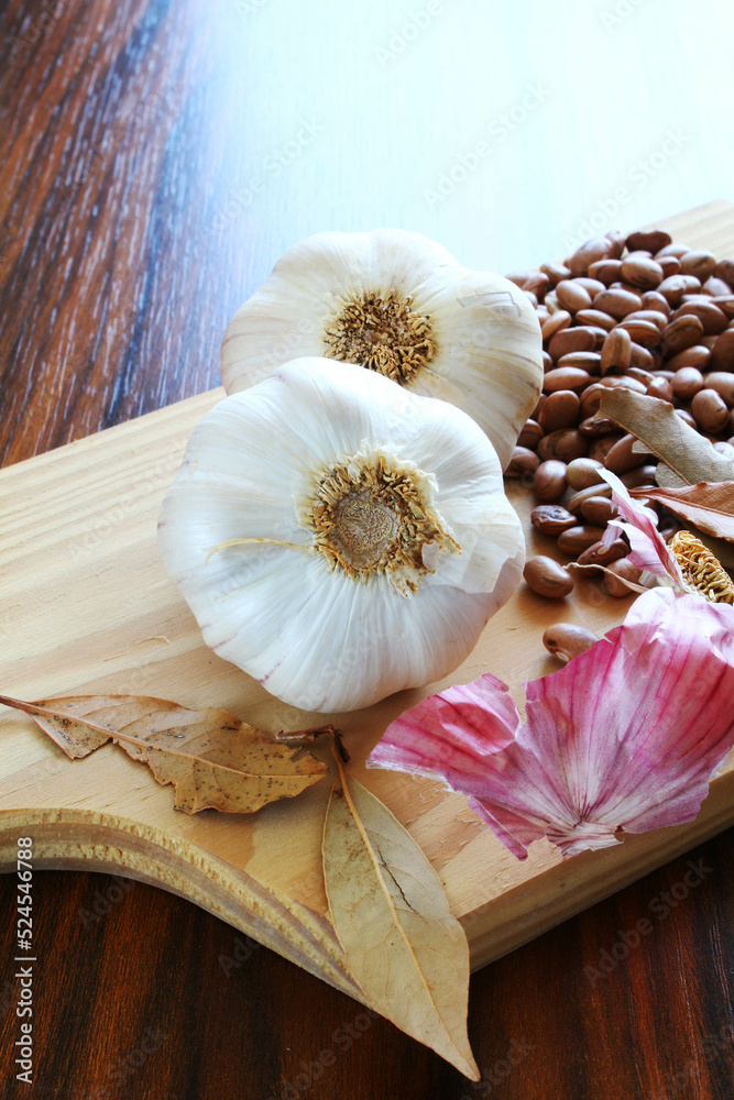 Garlic bulbs. Closeup of garlic bulb with bay leaves and carioca beans on the cutting board. Garlic bulbs. Closeup of garlic bulb with bay leaves and carioca beans on the cutting board.