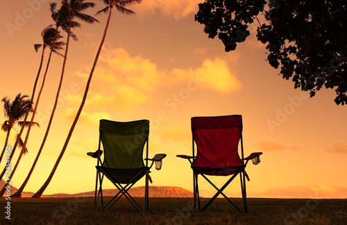 silhouette of two chairs at tropical sunset 