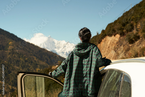 asian woman female tourist looking at snow covered mount kawaboge in yunnan, china, focus on foreground photo
