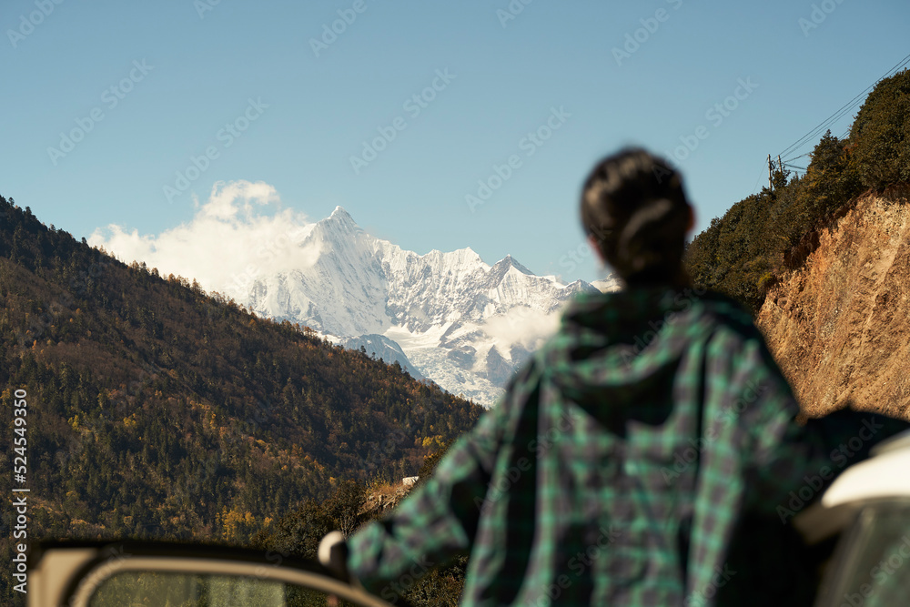 asian woman female tourist looking at snow covered mount kawaboge in yunnan, china, focus on backgrround